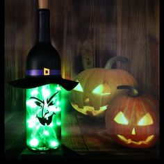 two jack o lantern pumpkins and a bottle of wine on a wooden table with lights