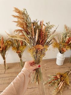 a person is arranging dried flowers on a table