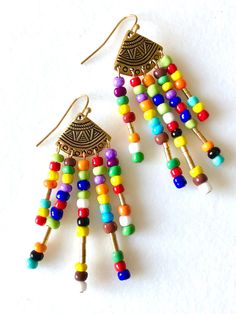 "Trendy multicolored seed bead chandelier earrings with golden tribal accents. Colorful tiny seed beads wire wrapped on gold plated pewter tribal fan shaped components made in USA. Lots of movement. Total drop is 2 5/8\"." Multicolor Round Beads Earrings With Gold Beads, Multicolor Beaded Earrings With Gold Beads As Gift, Traditional Multicolor Beaded Earrings With Gold Beads, Multicolor Drop Earrings With Gold Beads, Multicolor Beaded Dangle Chandelier Earrings, Multicolor Dangle Beaded Earrings With Tiny Beads, Multicolor Dangle Beaded Earrings With Gold Beads, Multicolor Dangle Beaded Earrings, Multicolor Tiny Beads Dangle Earrings