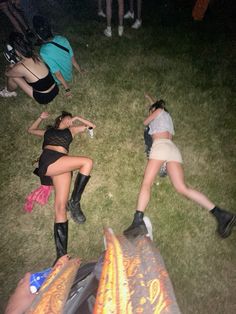 several people laying on the grass in front of an open fire pit at night time