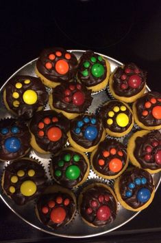 cupcakes with chocolate frosting and colorful candies on top are arranged in the shape of paw prints