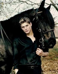 a man standing next to a black horse