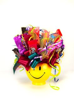 a smiley face vase filled with assorted candy and confetti on a white background