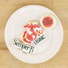 two decorated cookies on a plate with the words usmc and marine corp printed on them