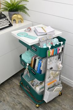 a green cart filled with lots of items on top of a wooden floor next to a desk