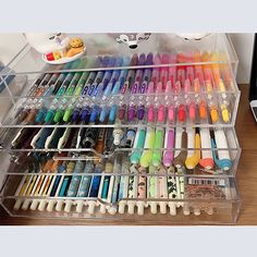 a drawer filled with lots of different types of markers and pens on top of a wooden table