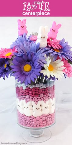 a vase filled with lots of purple flowers and bunny candies on top of it