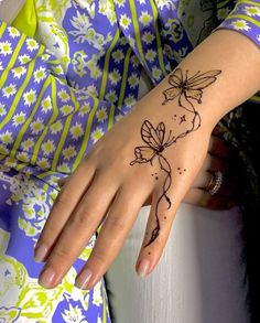 a woman's hand with a butterfly tattoo on her left wrist and the outline of a flower