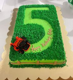 a birthday cake with green grass and a red toy truck on it's side