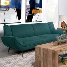 a living room with green couches and paintings on the wall above them, along with a coffee table