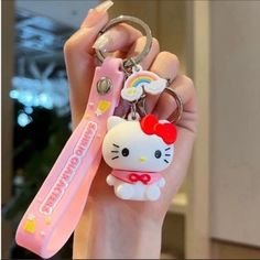 a hello kitty keychain is being held by a person with a pink bow