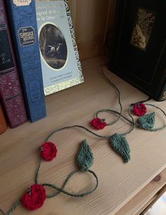 some crocheted flowers are on a table next to books and a book case