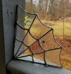 an old stained glass window with spider webs on it's side, in front of a grassy area