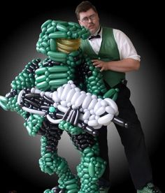 a man standing next to an inflatable green and white motorcycle with balloons on it