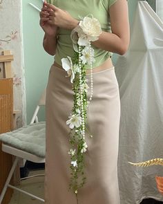 a woman standing in a room with flowers on her head and wearing a long skirt