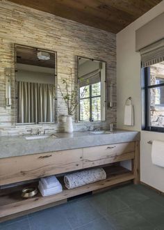 a bathroom with two sinks, mirrors and towels on the counter top in front of a window