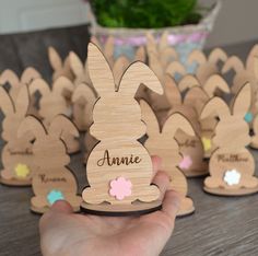 a person holding up some wooden bunny shaped magnets