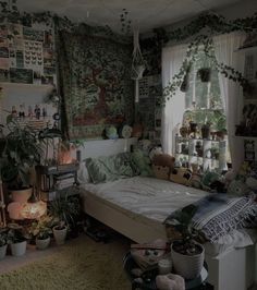 an unmade bed in a room with plants and stuffed animals on the wall behind it