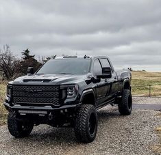 a large black truck parked on top of a gravel road