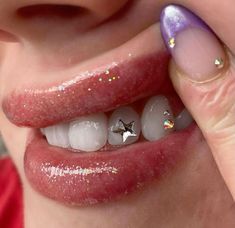 a woman with pink nails and white teeth has silver stars on her nose, while she is holding the top part of her mouth