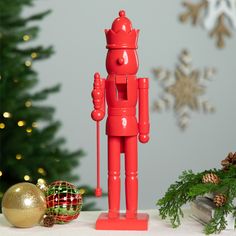 a red toy standing next to a christmas tree