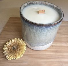 a white candle sitting on top of a wooden table next to a flower