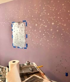 the wall is being painted with purple paint and stars on it, along with some tape