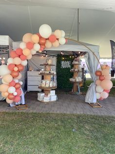 an outdoor market with balloons on the ground and tables full of goods in front of it