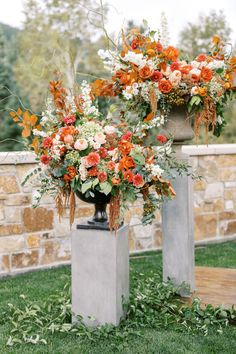 two cement vases with flowers on top of them