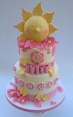 a three tiered cake decorated with pink and yellow decorations