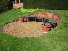 a brick bench sitting in the middle of a green yard with potted plants on it