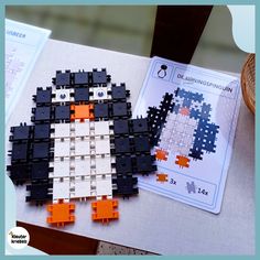 a penguin made out of legos sitting on top of a table next to a piece of paper