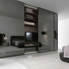 a bedroom with a bed, television and mirror closet doors in it's corner