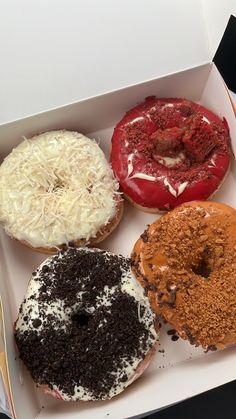 four donuts with different toppings in a box