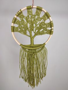 a green macrame hanging with a tree on it's side and two circles around it