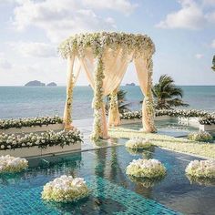 an outdoor wedding setup with white flowers and greenery on the water's edge