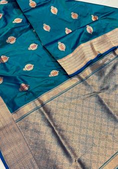 This Anar Buta Banarasi Katan silk saree in a mesmerizing peacock blue is a stunning celebration of traditional artistry and rich color. The deep, vibrant peacock blue hue provides a striking foundation, highlighting the intricate Anar buta patterns that adorn the fabric. These floral motifs, beautifully embellished with meenakari detailing, add a touch of vibrant artistry and depth, with hand-painted elements that bring each design to life. Crafted from luxurious Katan silk, the saree drapes gracefully, combining opulent texture with timeless elegance. Ideal for special occasions, this saree blends classic Banarasi craftsmanship with a bold, contemporary color, making it a standout piece that exudes both sophistication and charm. SILK MARK CERTIFIED This saree is ready to wear with fall a Luxury Designer Katan Silk Blouse Piece, Peacock Blue Saree Silk Blouses, Luxury Katan Silk Blouse Piece With Self Design, Luxury Katan Silk Saree With Meenakari Detail, Luxury Katan Silk Saree With Cutdana Detailing, Meenakari Saree, Saree Drapes, Banarasi Katan Silk Saree, Katan Silk Saree