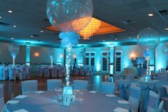 a banquet hall decorated with blue and white linens, silver tablecloths and balloons