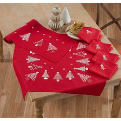 the table is covered with red napkins and place mats, which are decorated with christmas trees