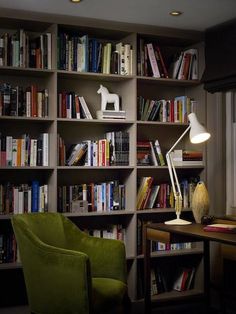 a green chair sitting in front of a book shelf filled with books