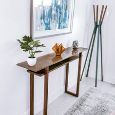 a wooden table topped with a plant next to a painting