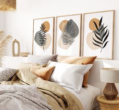 a bed with pillows and blankets on top of it next to two framed art pieces