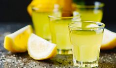 three glasses filled with lemonade sitting on top of a table next to sliced lemons