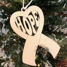 a wooden ornament shaped like a heart with the word hope on it hanging from a christmas tree