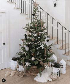 a small christmas tree in a basket on the floor next to some presents and stairs