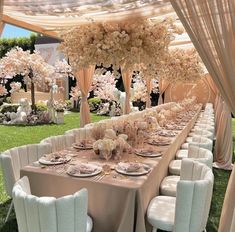 a table set up for an event with flowers on the tables and chairs around it