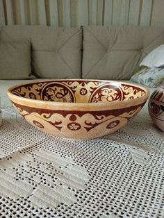 a wooden bowl sitting on top of a table next to two vases and a couch