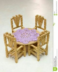 a wooden table with chairs and a crocheted doily on the table top