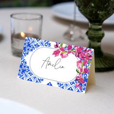 a place card sitting on top of a table next to a vase filled with flowers