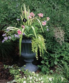 a planter filled with flowers and greenery in a garden